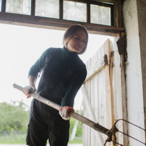 Lady cleaning out a stable